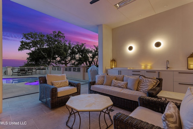 patio terrace at dusk featuring an outdoor hangout area and a fenced in pool