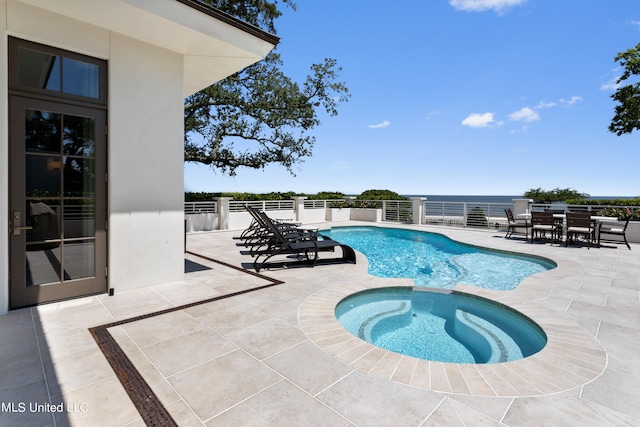 view of pool with a patio area, an in ground hot tub, and a water view