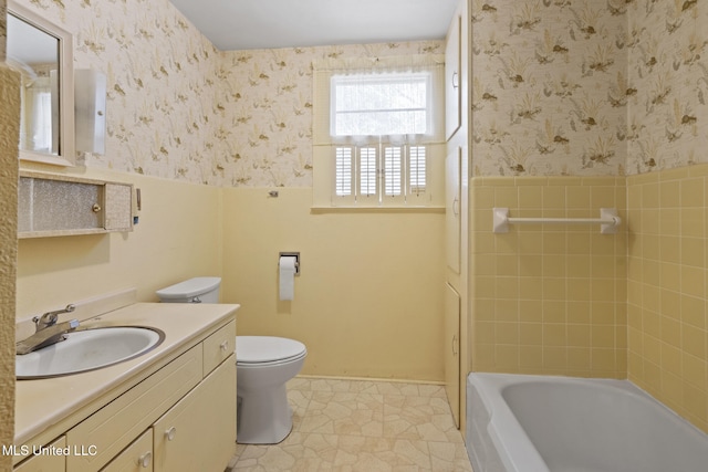 bathroom with vanity, toilet, wainscoting, and wallpapered walls