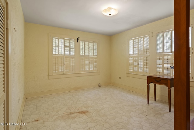 empty room featuring baseboards and a textured wall