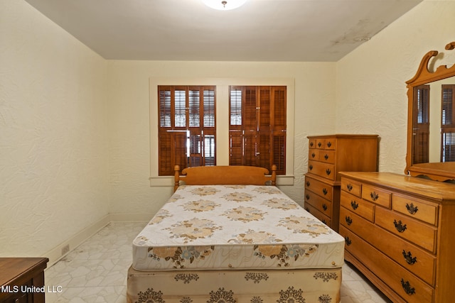 bedroom featuring baseboards and a textured wall