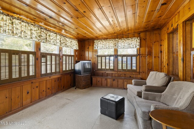 living area featuring wooden ceiling, light colored carpet, and wood walls