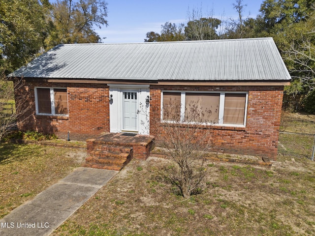 view of front of home featuring metal roof and brick siding