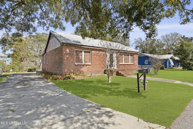 ranch-style house featuring brick siding, driveway, metal roof, and a front yard