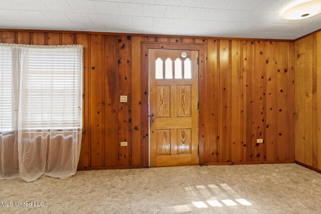 carpeted entrance foyer featuring wood walls