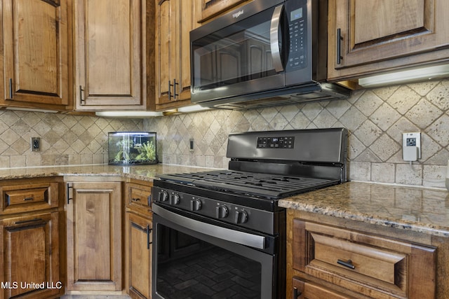 12219 County Farm Rd, Gulfport, MS 39503 - kitchen featuring stainless steel gas range oven, decorative backsplash, light stone countertops, and brown cabinets