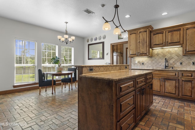 12219 County Farm Rd, Gulfport, MS 39503 - kitchen with backsplash, a kitchen island, hanging light fixtures, stone counters, and recessed lighting