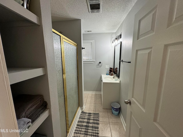 bathroom with vanity, a textured ceiling, tile patterned flooring, and a shower with door