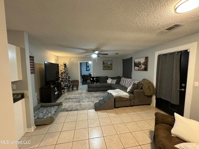 living room featuring ceiling fan, a textured ceiling, and light tile patterned floors