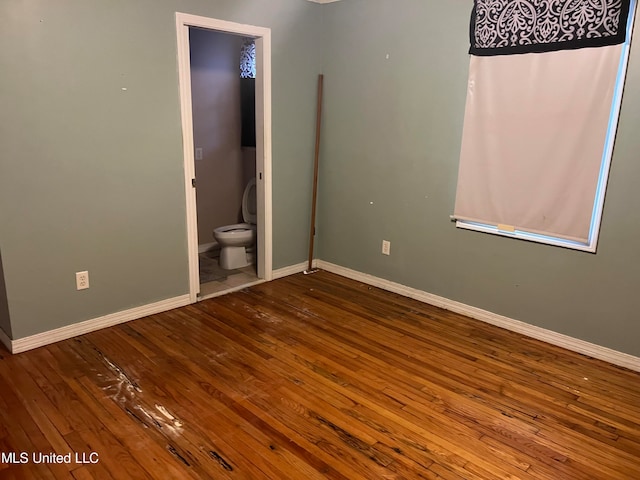 unfurnished bedroom featuring connected bathroom and hardwood / wood-style floors