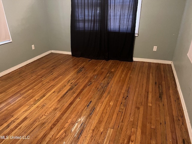 empty room with baseboards and hardwood / wood-style flooring
