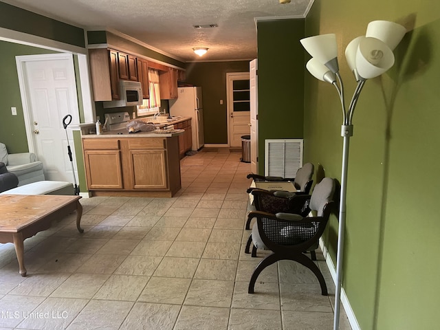 kitchen with a textured ceiling, visible vents, white appliances, light countertops, and ornamental molding