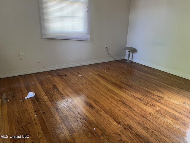 spare room featuring hardwood / wood-style flooring and baseboards