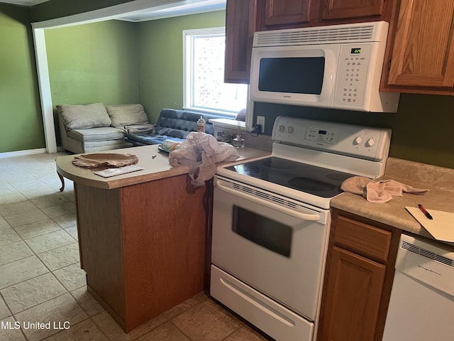 kitchen featuring a peninsula, open floor plan, white appliances, brown cabinetry, and light countertops