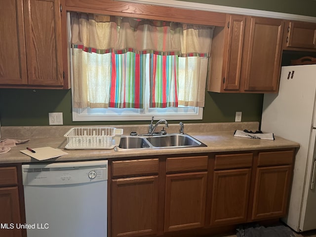 kitchen with light countertops, brown cabinets, a sink, and white appliances