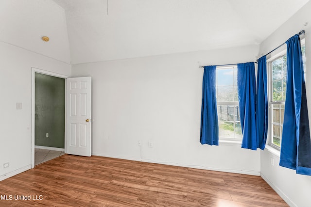 unfurnished room with hardwood / wood-style floors, a healthy amount of sunlight, and vaulted ceiling