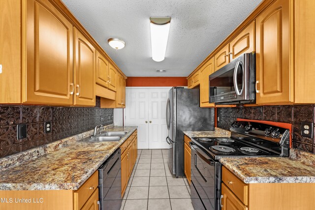 kitchen with light stone counters, a textured ceiling, black appliances, and light tile patterned floors