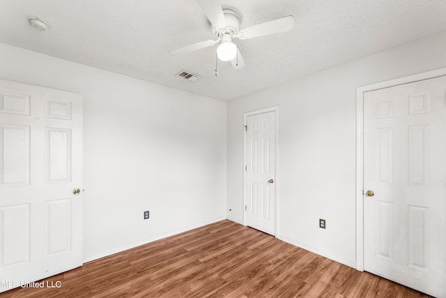 unfurnished bedroom featuring hardwood / wood-style floors, a textured ceiling, and ceiling fan