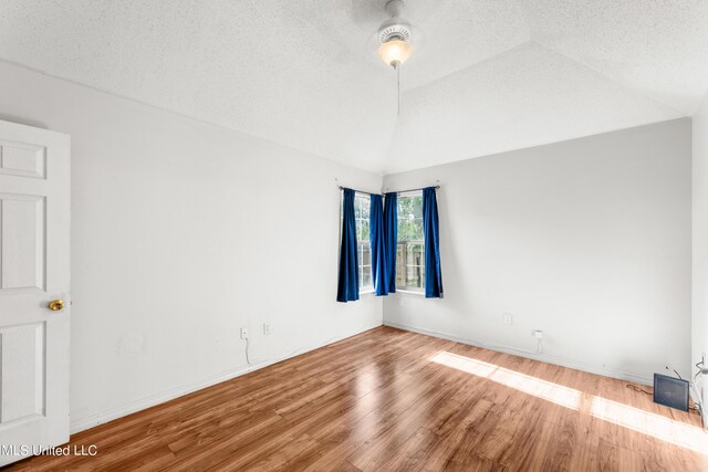 11318 Fairfield Ln, Gulfport, MS 39503 - empty room with baseboards, wood finished floors, a textured ceiling, and vaulted ceiling