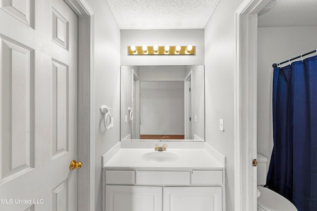 bathroom with toilet, a textured ceiling, and vanity