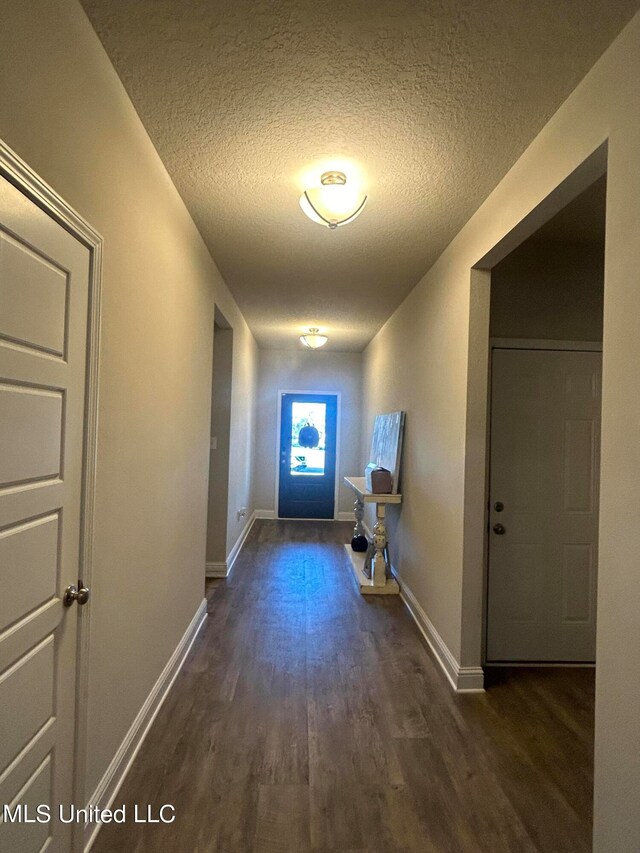 hall featuring dark wood-type flooring and a textured ceiling