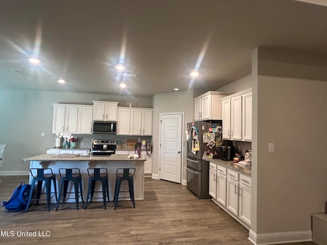 kitchen with white cabinetry, appliances with stainless steel finishes, a kitchen island with sink, and tasteful backsplash