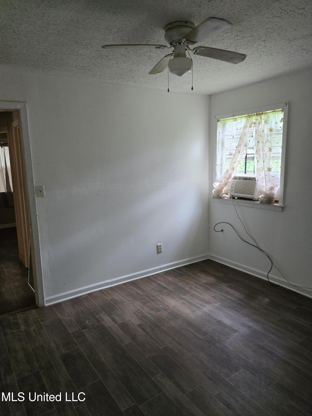 spare room featuring cooling unit, dark wood-style flooring, a textured ceiling, and baseboards