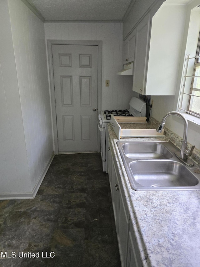 kitchen with white range with gas stovetop, white cabinets, light countertops, under cabinet range hood, and a sink