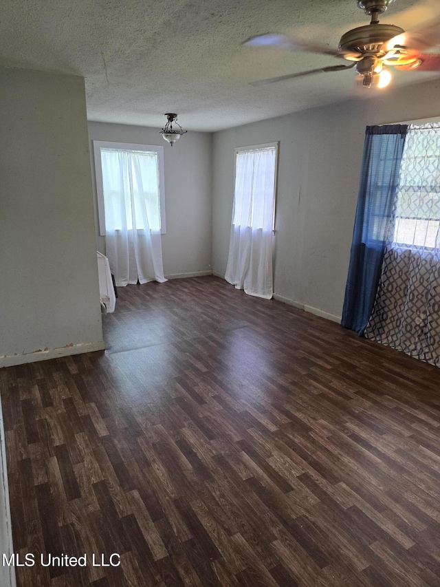 unfurnished room featuring radiator, dark wood-style flooring, plenty of natural light, and a textured ceiling