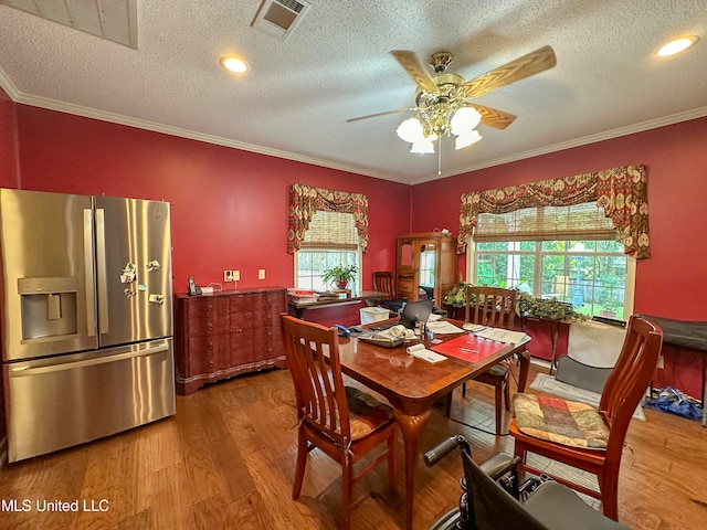 dining room featuring ceiling fan, a textured ceiling, wood-type flooring, and ornamental molding