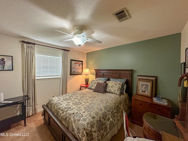 bedroom featuring a textured ceiling, light colored carpet, and ceiling fan