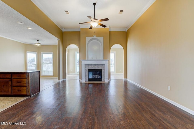 unfurnished living room with ceiling fan, a healthy amount of sunlight, a fireplace, and a textured ceiling