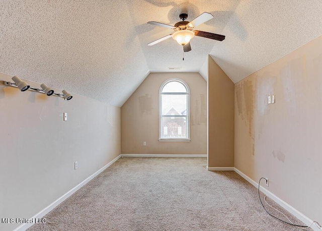 additional living space with ceiling fan, a textured ceiling, light carpet, and vaulted ceiling