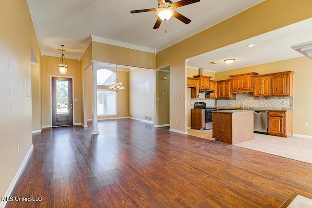 kitchen with ceiling fan with notable chandelier, appliances with stainless steel finishes, a kitchen island, tasteful backsplash, and ornamental molding