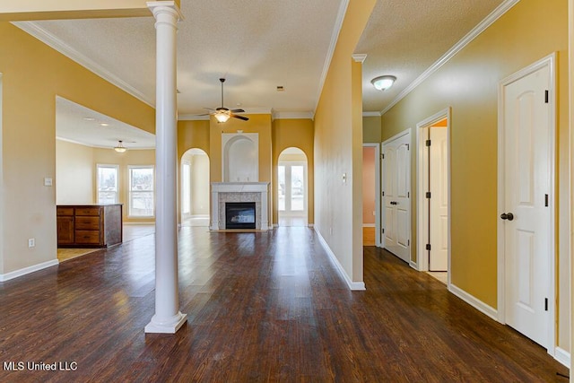 unfurnished living room with a textured ceiling, ceiling fan, decorative columns, a tile fireplace, and crown molding