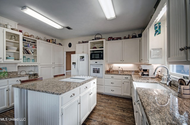 kitchen featuring white appliances, white cabinetry, and a center island