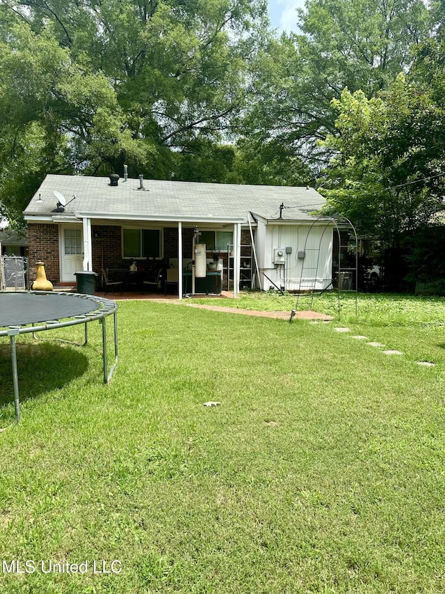 8215 Whitehead Dr, Southaven, MS 38671 - rear view of house with a trampoline, a lawn, and view of wooded area