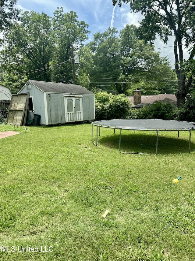 8215 Whitehead Dr, Southaven, MS 38671 - view of grassy yard featuring a trampoline, a storage shed, and view of wooded area