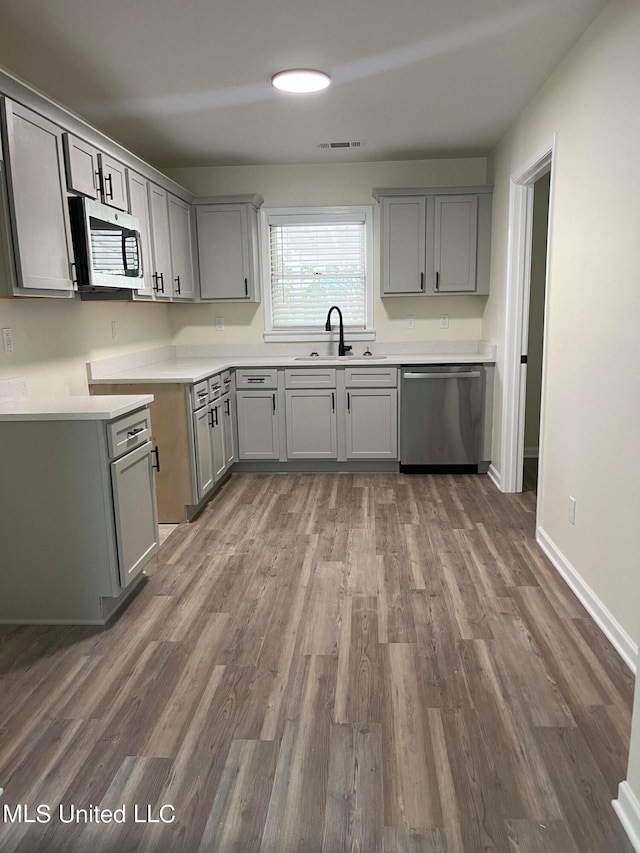 kitchen featuring sink, gray cabinetry, stainless steel appliances, and dark hardwood / wood-style flooring