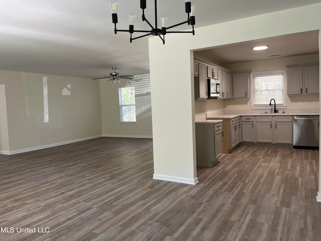 kitchen with dark wood-type flooring, sink, gray cabinets, appliances with stainless steel finishes, and ceiling fan with notable chandelier