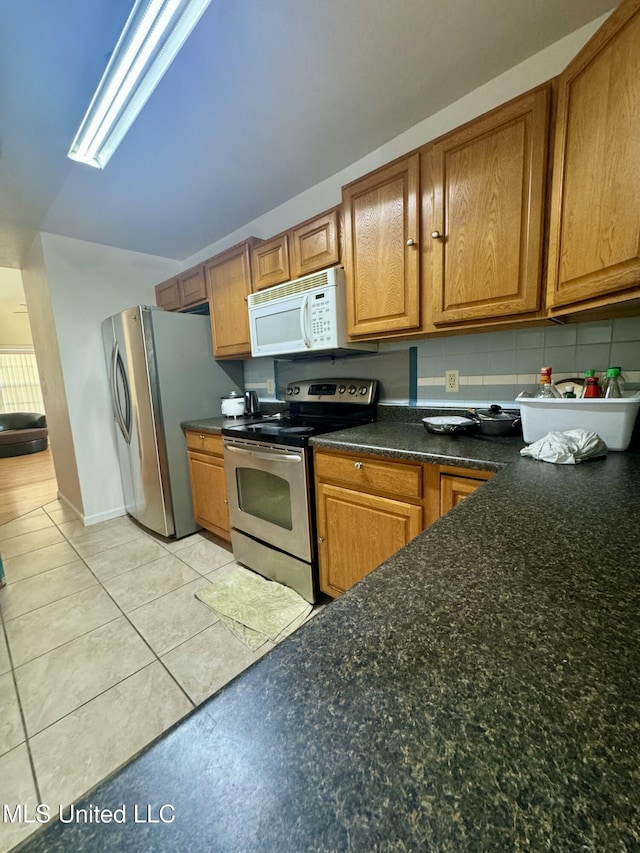 kitchen featuring light tile patterned floors, brown cabinets, and stainless steel appliances