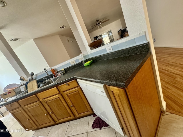 kitchen with ceiling fan, decorative backsplash, dishwasher, dark countertops, and brown cabinets