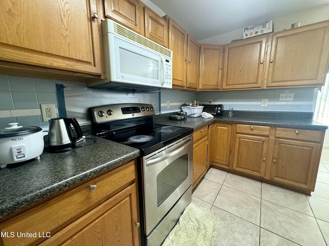 kitchen with electric range, tasteful backsplash, dark countertops, light tile patterned floors, and white microwave