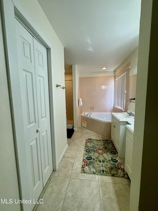 bathroom with a bath, a shower stall, a textured ceiling, and vanity