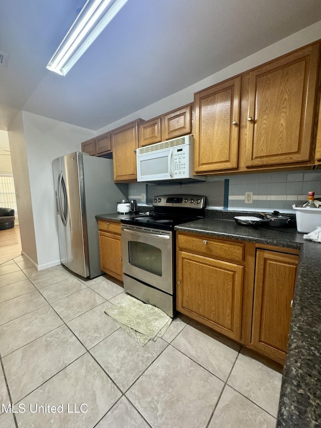 kitchen featuring light tile patterned floors, brown cabinets, and stainless steel appliances