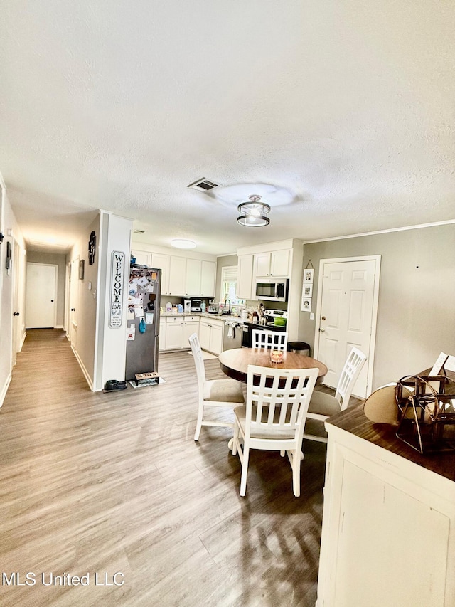 412 Monica Ln, Pearl, MS 39208 - dining space with light wood finished floors, a textured ceiling, and baseboards