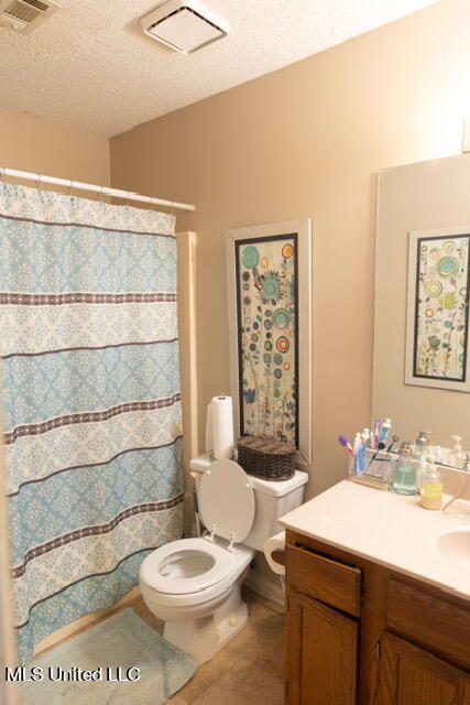 bathroom featuring vanity, a shower with shower curtain, a textured ceiling, and toilet