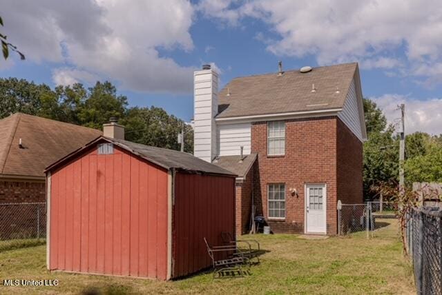 rear view of property featuring a storage unit and a yard