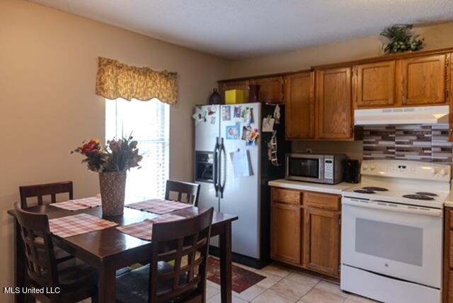 kitchen with appliances with stainless steel finishes, light tile patterned flooring, and decorative backsplash