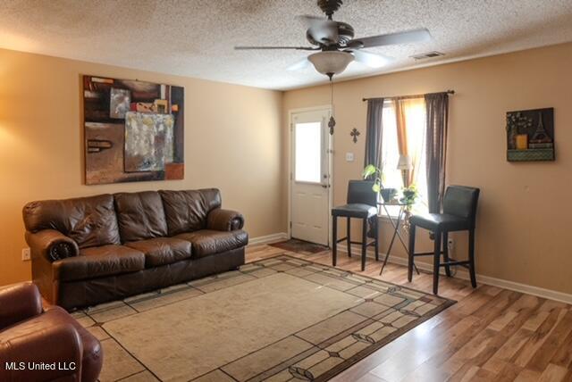 living room with ceiling fan, a textured ceiling, and hardwood / wood-style floors